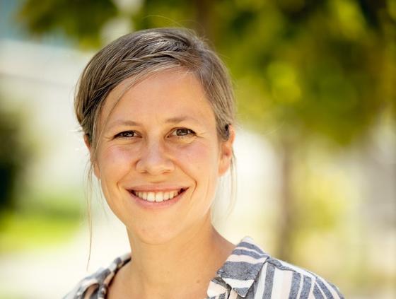 Cornelia Marschall,﻿ ganzheitliche Kinesiologin in Luzern lächelt in die Kamera, im Hintergrund sanfte Grüntöne aus der Natur